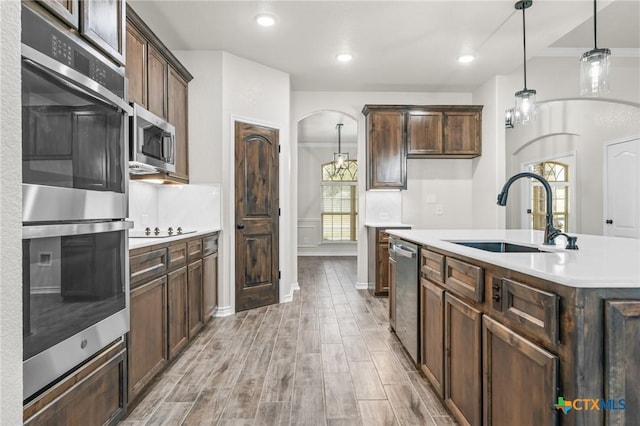 kitchen with sink, dark brown cabinets, a center island with sink, and appliances with stainless steel finishes