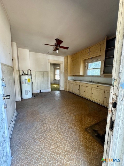 kitchen with ceiling fan, sink, light brown cabinetry, and water heater