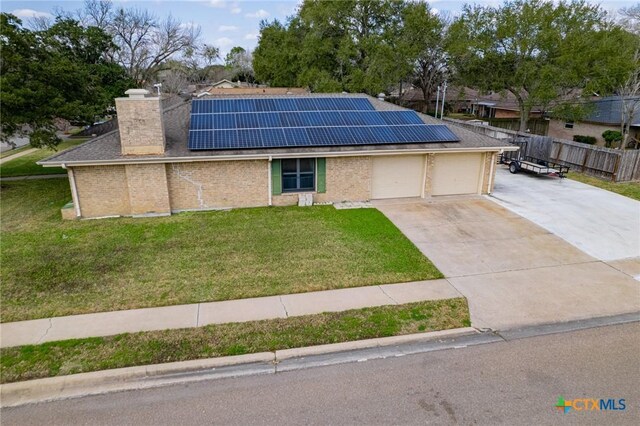 view of front of property with a garage, a front lawn, and solar panels