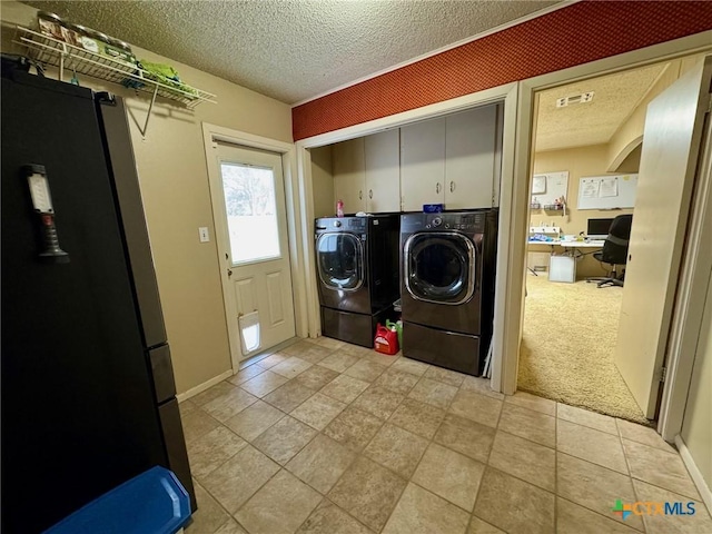 clothes washing area featuring light carpet, washing machine and dryer, cabinets, and a textured ceiling