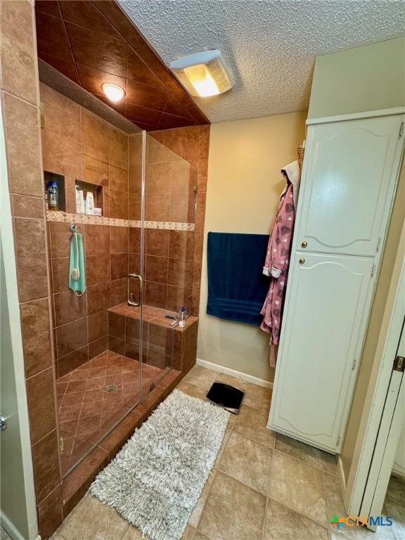 bathroom with a shower with door and a textured ceiling