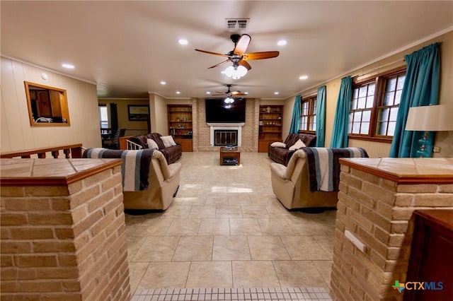 tiled living room featuring ornamental molding, ceiling fan, a fireplace, and built in shelves