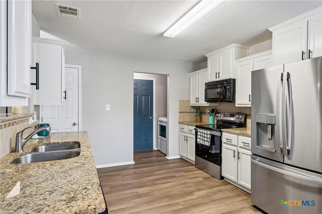 2617 Turning Creek St, Temple, TX 76504 - kitchen with appliances with stainless steel finishes, light wood finished floors, white cabinets, backsplash, and light stone counters