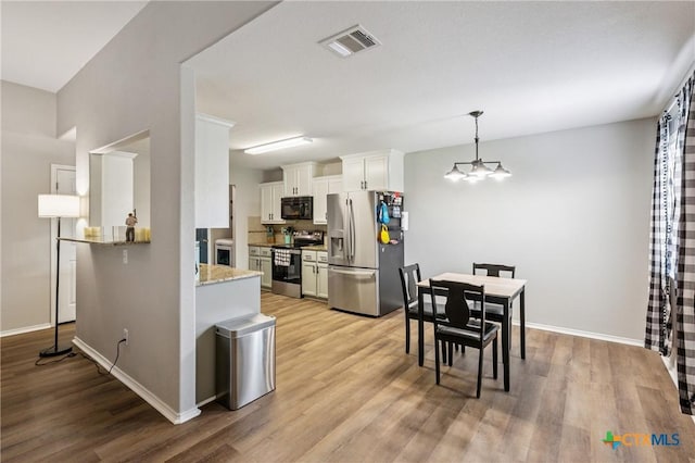 2617 Turning Creek St, Temple, TX 76504 - kitchen with appliances with stainless steel finishes, light wood-style flooring, white cabinetry, light stone countertops, and a peninsula