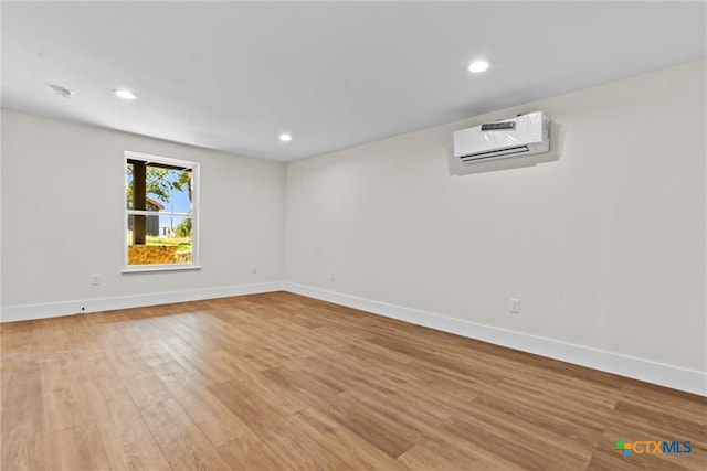 empty room featuring an AC wall unit and light hardwood / wood-style floors