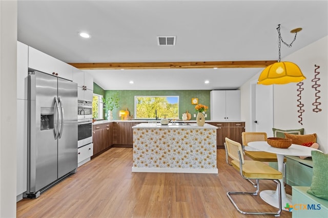 kitchen with stainless steel appliances, light hardwood / wood-style floors, white cabinets, pendant lighting, and lofted ceiling with beams