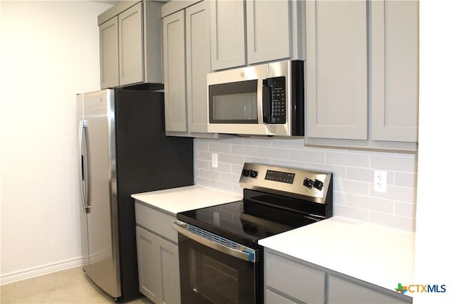 kitchen with gray cabinets, backsplash, and stainless steel appliances