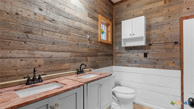 bathroom featuring vanity, wooden walls, and toilet