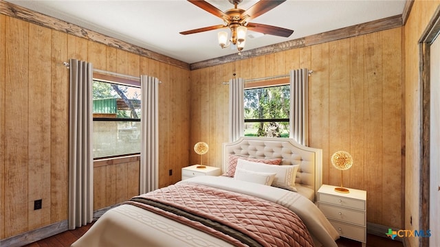 bedroom featuring hardwood / wood-style flooring, multiple windows, wooden walls, and ceiling fan