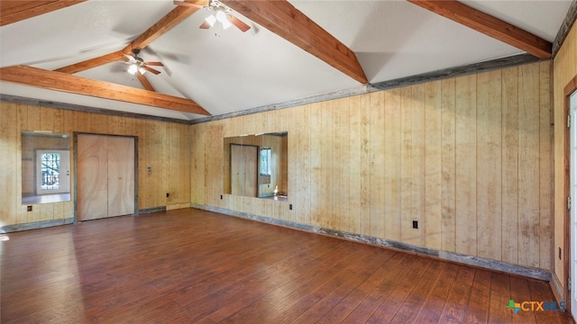 spare room with dark hardwood / wood-style flooring, wood walls, vaulted ceiling with beams, and ceiling fan