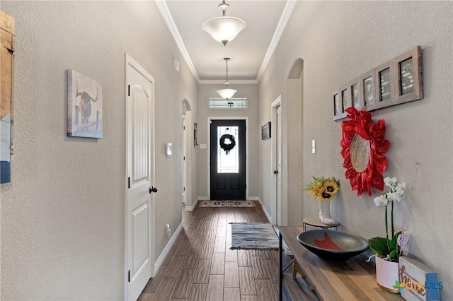 foyer entrance with baseboards, arched walkways, wood finished floors, and ornamental molding