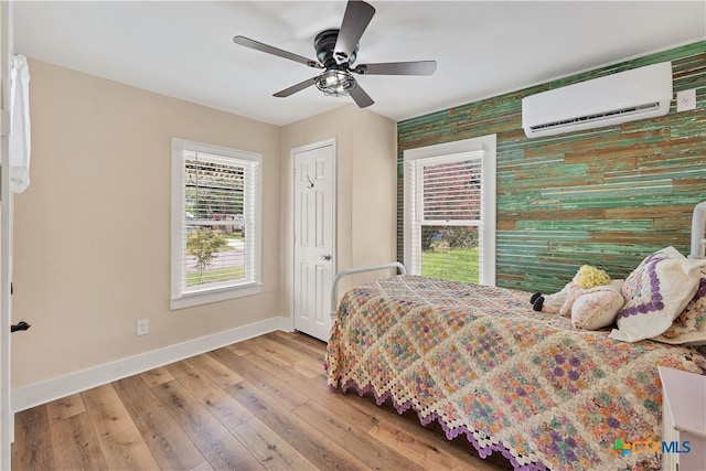 bedroom featuring light hardwood / wood-style floors, ceiling fan, and a wall mounted AC