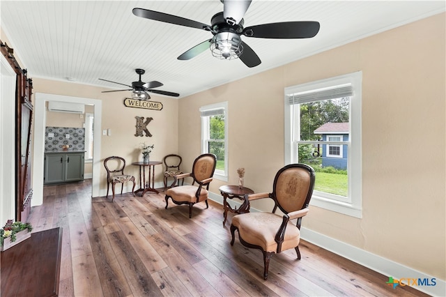 sitting room with a wealth of natural light, a barn door, hardwood / wood-style flooring, and a wall mounted AC