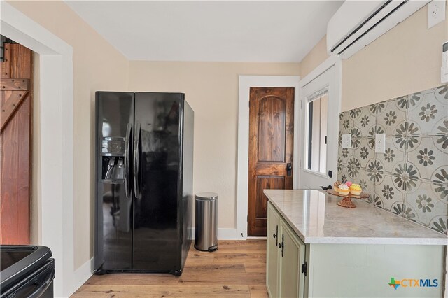 kitchen with green cabinets, light hardwood / wood-style flooring, black appliances, and a wall mounted AC