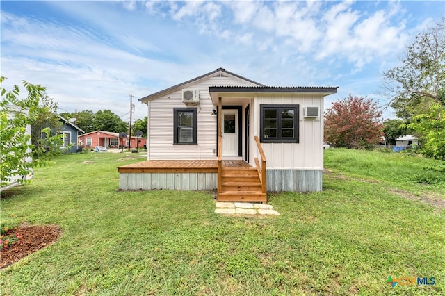 view of front of home with an AC wall unit and a front lawn