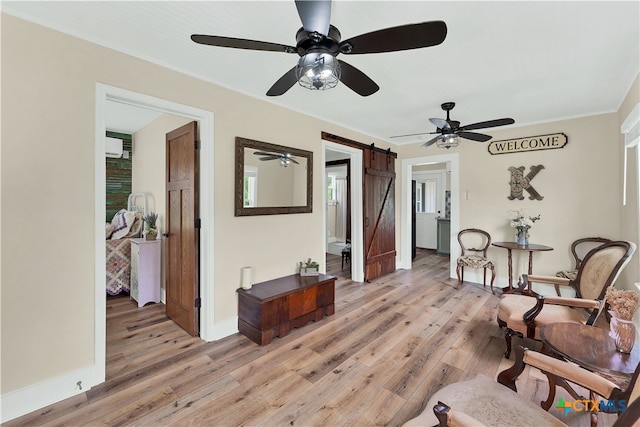 sitting room featuring ceiling fan, a barn door, and light hardwood / wood-style floors