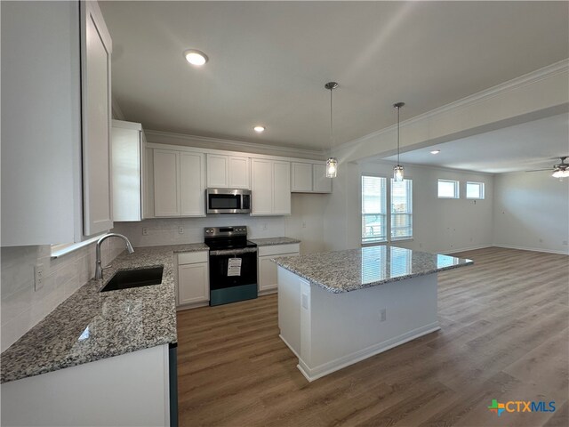 kitchen featuring light hardwood / wood-style floors, stainless steel appliances, sink, a kitchen island, and white cabinetry