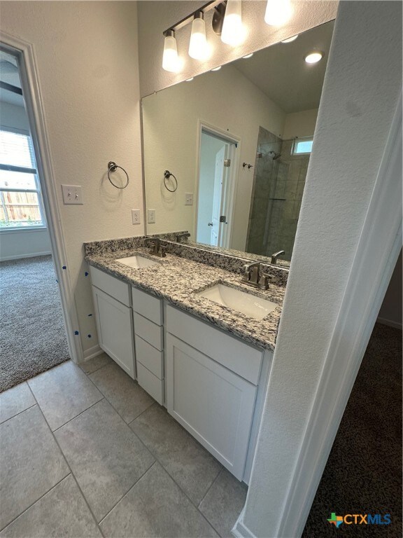 bathroom featuring vanity, tile patterned flooring, and a tile shower