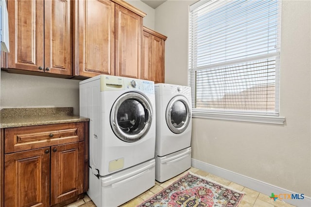 clothes washing area with cabinets, light tile patterned flooring, and washer and clothes dryer