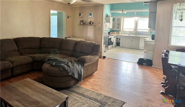 living room with a chandelier, sink, a healthy amount of sunlight, and light wood-type flooring