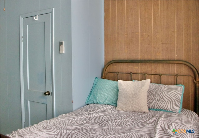 bedroom featuring wooden walls