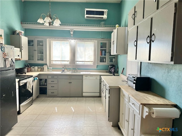 kitchen featuring stainless steel range with electric stovetop, white dishwasher, black fridge, sink, and hanging light fixtures