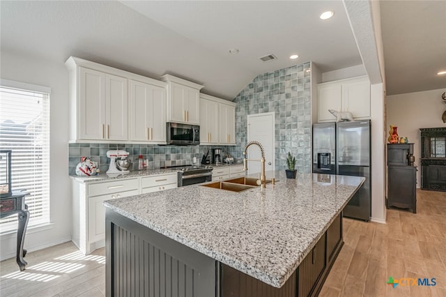 kitchen featuring stainless steel appliances, white cabinetry, and a kitchen island with sink