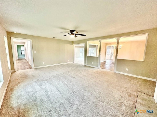 spare room with ceiling fan with notable chandelier, light colored carpet, and a textured ceiling