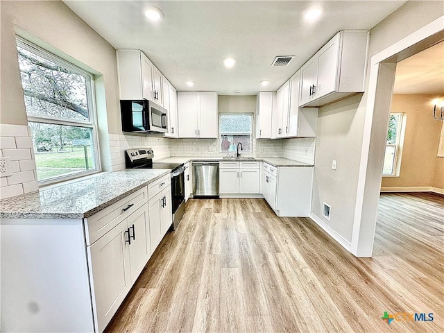 kitchen featuring white cabinets, stainless steel appliances, light stone counters, and sink