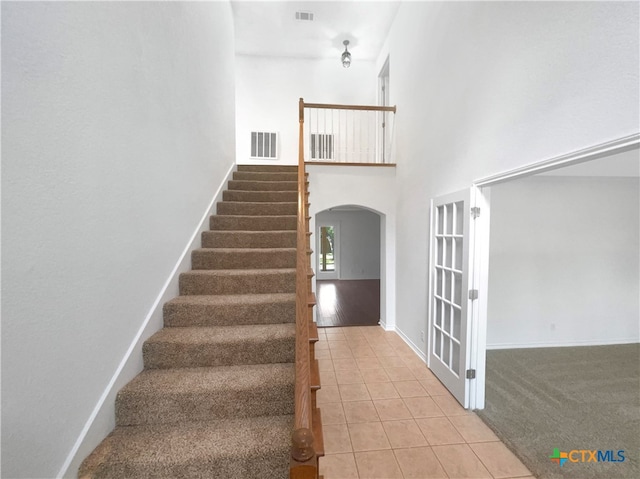 stairway featuring a towering ceiling and tile patterned flooring