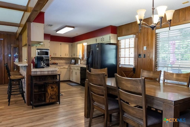 3309 Cottonwood Ln, Temple, TX 76502 - dining space with a chandelier, light wood finished floors, and wooden walls