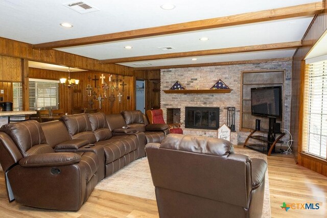 3309 Cottonwood Ln, Temple, TX 76502 - living room featuring light wood-style flooring, a chandelier, a brick fireplace, beam ceiling, and wooden walls
