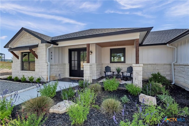 438 Cedar Mountain Dr, Marble Falls, TX 78654 - property entrance featuring french doors, stone siding, a shingled roof, covered porch, and board and batten siding