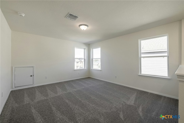 empty room featuring a textured ceiling and dark carpet