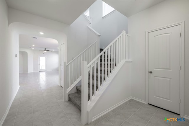 stairway with tile patterned floors and ceiling fan