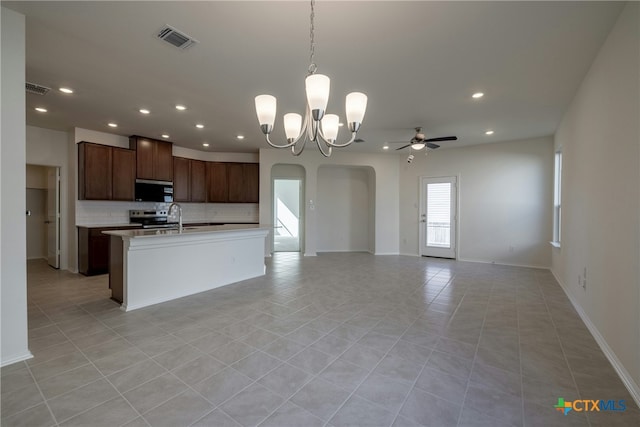 kitchen with pendant lighting, backsplash, ceiling fan with notable chandelier, light tile patterned floors, and appliances with stainless steel finishes