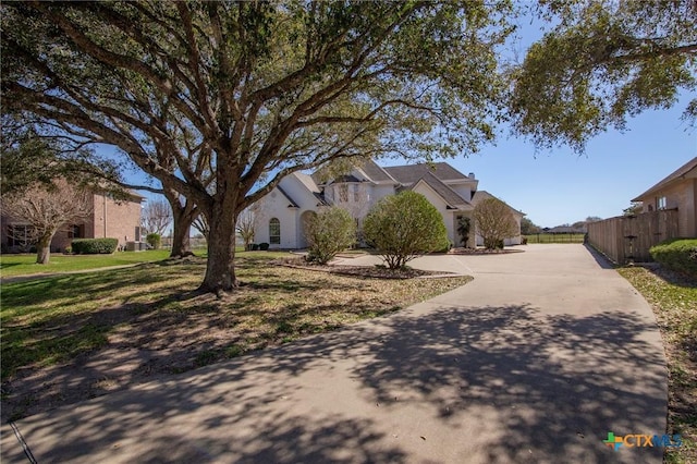 exterior space featuring driveway, a front lawn, and fence