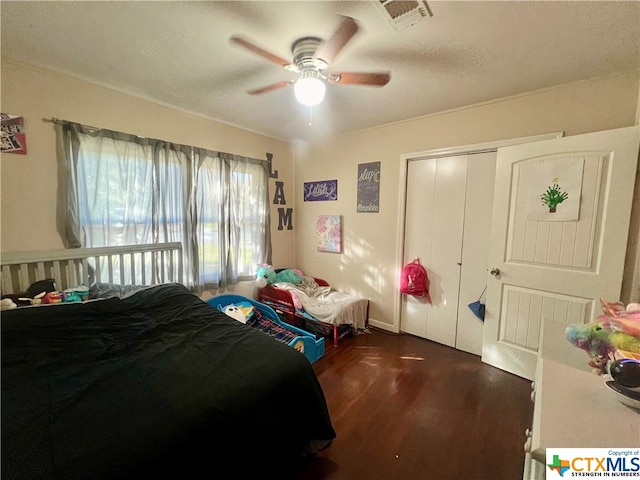 bedroom with dark wood-type flooring, ceiling fan, and a closet