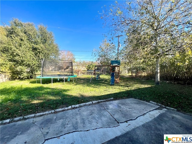 view of yard featuring a patio area, a playground, and a trampoline