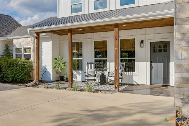 entrance to property with a standing seam roof, metal roof, a porch, and board and batten siding