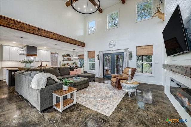 living room featuring beam ceiling, an inviting chandelier, and a high ceiling