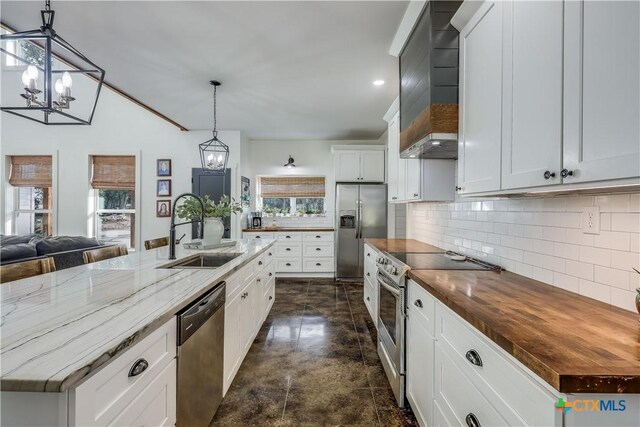 kitchen with white cabinets, decorative light fixtures, and a center island with sink