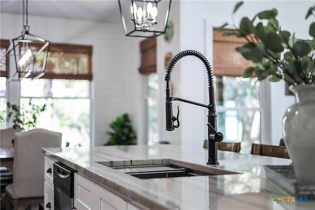 kitchen featuring plenty of natural light, white cabinetry, sink, and hanging light fixtures