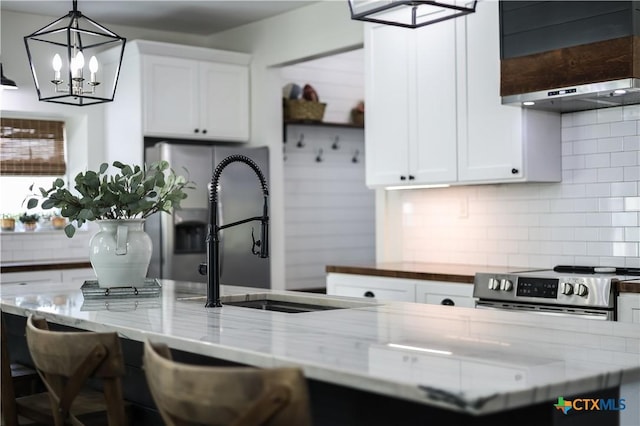 kitchen with light stone counters, white cabinetry, stainless steel stove, and tasteful backsplash