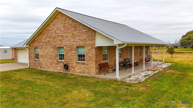 rear view of house with a porch, a garage, a yard, and a patio