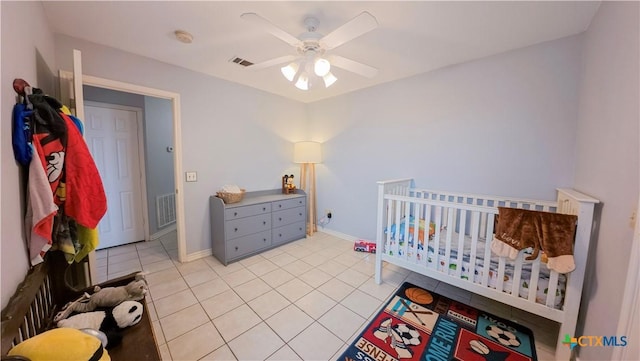 bedroom featuring light tile patterned flooring, a nursery area, and ceiling fan