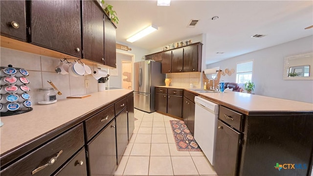 kitchen featuring stainless steel refrigerator, sink, backsplash, dark brown cabinetry, and white dishwasher