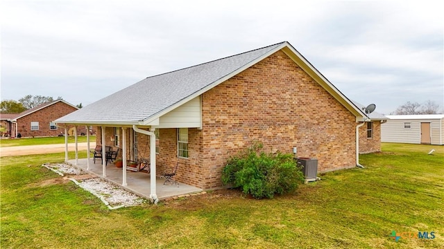 view of side of home with cooling unit, a yard, and a patio area