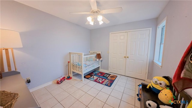 tiled bedroom featuring a closet, a nursery area, and ceiling fan