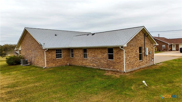 rear view of property with a lawn and central air condition unit